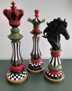 three decorative chess pieces with a horse head on each one and a crown on the other