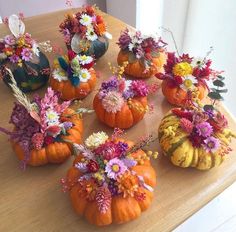 several pumpkins with flowers in them sitting on a table next to other small vases