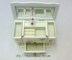 an open white jewelry box with drawers on the top and one drawer in the bottom