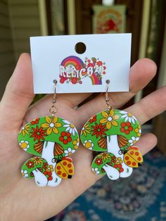 Get ready to embrace the spirit of the 70s with these Green and Groovy Flower Mushroom Bunch Earrings. Inspired by the retro vibes of the era, these earrings feature a delightful bunch of mushrooms filled with flowers and in vibrant colors. Crafted from lightweight acrylic and adorned with gold-coated stainless steel hooks, these earrings offer a perfect blend of comfort, style, and nostalgia. Product Details: Size: Each earring measures approximately 2 3/4 inches from the top of the hook to the Whimsical Green Mushroom Design Earrings, Whimsical Green Mushroom Earrings, Retro Multicolor Flower Earrings For Gift, Retro Summer Earrings As Gifts, Retro Summer Earrings As A Gift, Retro Spring Flower Earrings Gift, Vintage Summer Flower Earrings, Spring Retro Flower Earrings Gift, Vintage Flower Earrings For Summer