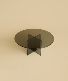 a round glass table with an abstract design on the top is shown in front of a beige background