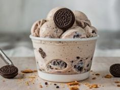 an oreo cookie ice cream in a bowl with two cookies on the table next to it