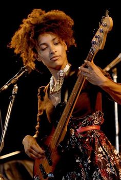 a woman with curly hair playing an electric guitar