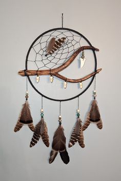 a dream catcher with feathers hanging from it's side and two birds on top