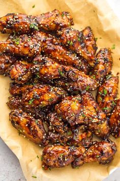 chicken wings covered in sesame seeds and garnished with parsley on parchment paper