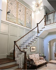 a staircase leading up to a living room with paintings on the wall and a couch