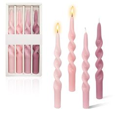 pink candles are lined up next to each other in a white box, with one lit candle between them