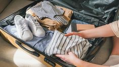 a woman packing her suitcase with clothes and shoes