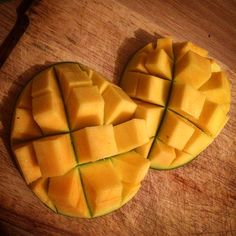 two slices of mango sitting on top of a wooden cutting board