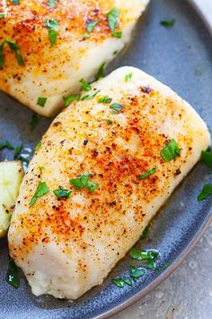 two pieces of chicken on a plate with parsley sprinkled on the side