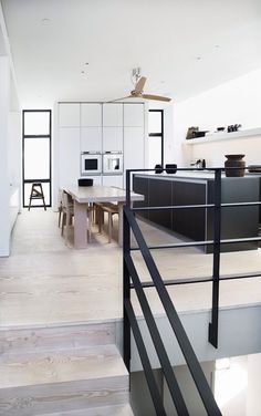 an open kitchen and dining area with stairs leading up to the upper floor that is white