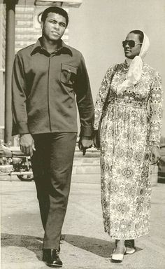 an old black and white photo of two people walking down the street with one holding hands