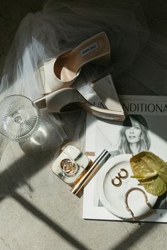 shoes and accessories are sitting on the floor next to a magazine with an image of a woman's face