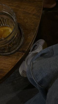 a glass bowl filled with liquid sitting on top of a table next to a person's legs