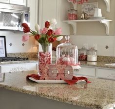 the kitchen counter is decorated with pink and white flowers in glass vases on it