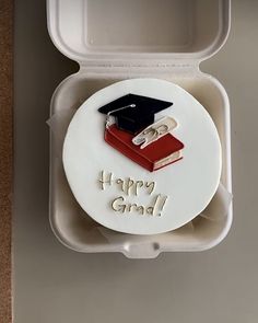 a cake in the shape of a graduation cap and book with happy grad written on it