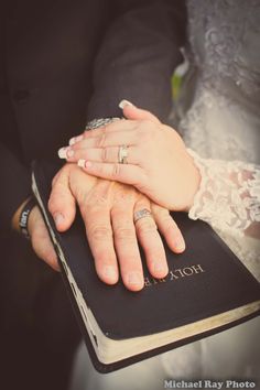 a bride and groom holding hands on top of a book