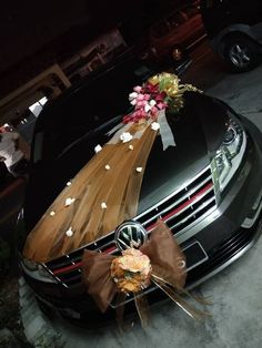 a black car with flowers on the hood and ribbons tied to it's side