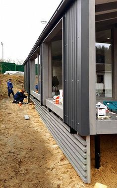 two men are working on the side of a building that's being built into dirt