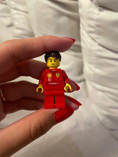 a hand holding a lego minifigure wearing a red dress