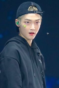 the young man is wearing a baseball cap and green eyeliners on his face