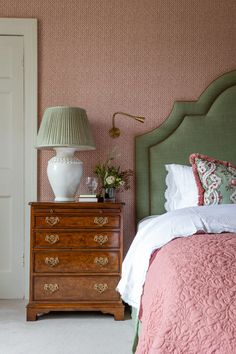 a bedroom with pink and green wallpaper, a white lamp and a bed in it