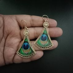 a pair of earrings with peacock feathers on them