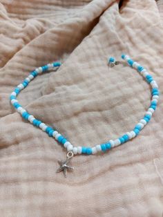 a blue and white beaded bracelet with a starfish charm on the end is laying on a bed