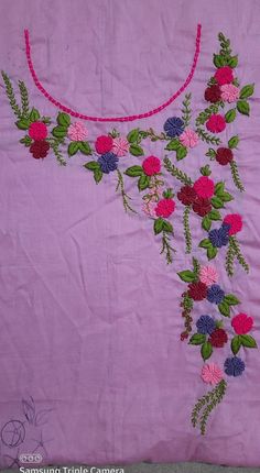 a pink table cloth with flowers and leaves embroidered on the side, along with a red string