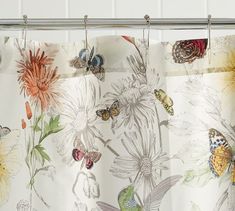 a shower curtain with butterflies on it and flowers in the background, hanging from a metal rod