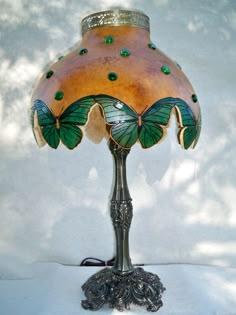 a lamp that is sitting on top of a white surface with green glass butterfly wings