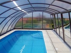 an indoor swimming pool with glass walls and windows on the sides, next to a tiled floor