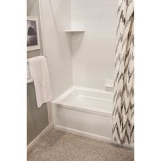 a white bath tub sitting next to a shower curtain in a bathroom on top of a carpeted floor