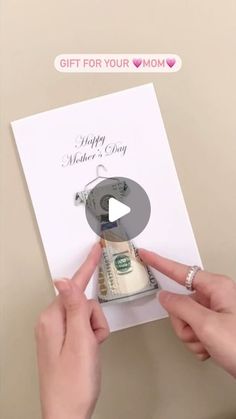 a person holding money in front of a card that says happy mother's day