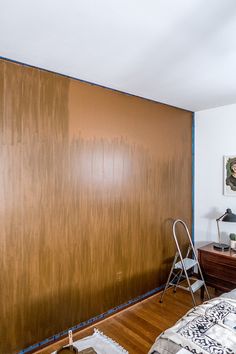 an empty room with wood paneling on the wall and a ladder leaning against the wall