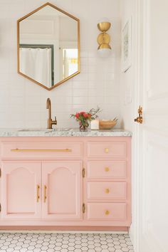 a bathroom with pink vanity and gold accents