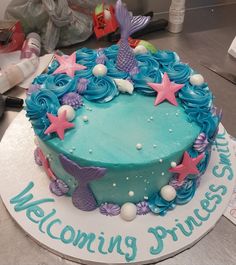 a birthday cake decorated with blue icing and pink starfish on a table next to other items