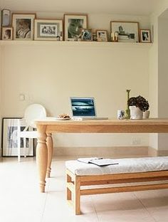 a wooden bench sitting in front of a table with a laptop on top of it