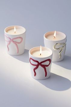 three candles with bows on them sitting next to each other in front of a white background