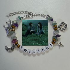 two people sitting on the ground with beads and charms around them that spell out twilight