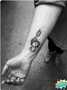 a black and white photo of a person's arm with a musical note tattoo on it