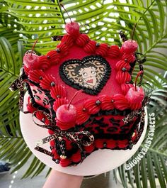 the cake is decorated with red and black icing, heart shaped decorations, and cherries