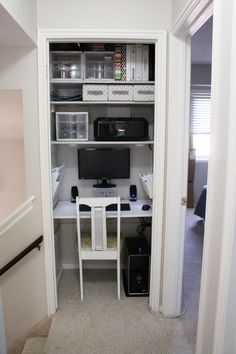 a computer desk sitting in the corner of a room next to a closet full of items