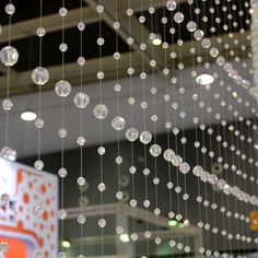 some clear beads hanging from the ceiling in a store or showroom with lights and signs