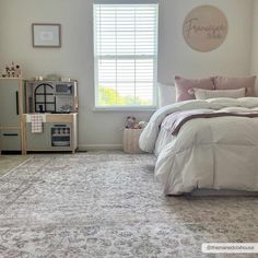 a bed room with a neatly made bed next to a window and a rug on the floor