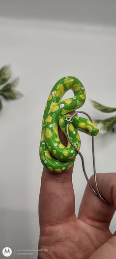 a hand holding a green and yellow snake figurine