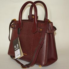 Authentic Burberry Python Leather Banner Derby Tote Bag Color: Mahogany Red New With Tags Made In Italy Retail: $3595 Rolled Top Handles With Keeper Strap, 4" Drop. Removable, Adjustable Shoulder Strap, 16" Drop. Open Top With Snap Closure. Belted Tabs Gather Sides Of Body. Logo Embossing At Bottom Center. Interior, Center Zip Compartment; One Zip And Two Slip Pockets. Canvas Lining. Metal Feet Protect Bottom. 10.2"W X 8"H X 4.5"D. Luxury Burgundy Shoulder Bag With Branded Hardware, Luxury Burgundy Crossbody Satchel, Luxury Burgundy Tote Satchel, Formal Burgundy Bags With Branded Hardware, Evening Burgundy Bag With Branded Hardware, Burgundy Evening Bag With Branded Hardware, Body Logo, Small Tote Bag, Small Tote