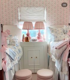 two twin beds in a bedroom with pink and white decor on the walls, along with matching foot stools