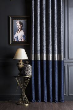 a room with a lamp and pictures on the wall, along with a blue curtain