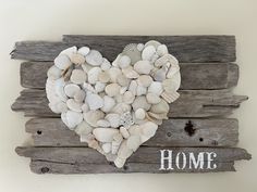 a heart made out of seashells sitting on top of a wooden plank wall